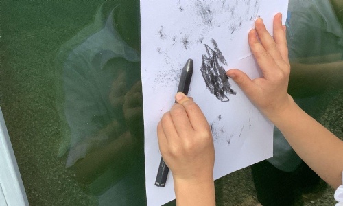 A Year 2 pupil making a texture rubbing with a crayon