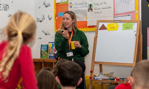 A teacher leading a phonics session with children on the carpet