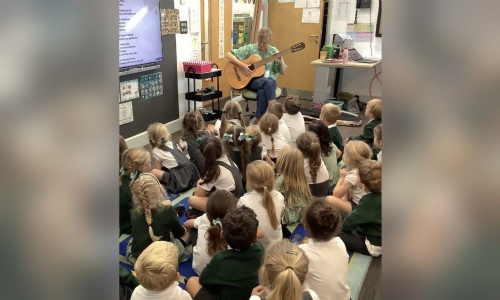 Mrs Paulson playing guitar and sharing harvest songs with Reception
